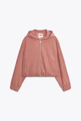 Chaqueta corta color rosa con capucha y manga larga terminada en puño. Tiene bolsillos de vivo en el delantero, bajo ajustable con cordones elásticos y cierre frontal con cremallera.