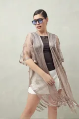 Poncho color beige de tejido calado con flecos en el ruedo.