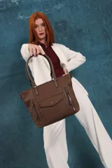 Cartera bandolera de símil cuero color marrón claro, con doble asa rígida y correa regulable. Presenta dos bolsillos frontales con cierre vertical y un bolsillo frontal con solapa y botón. Cuenta con dos divisiones internas.