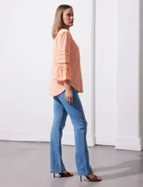 Blusa color celeste con escote en V, mangas largas acampanadas con detalle de crochet y frunces en los hombros.