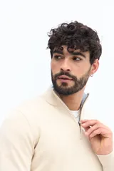 Sweater de tejido liso color verde oscuro, con cuello medio y cierre frontal parcial plateado. Presenta puños y cintura acanalados, y un pequeño logo bordado en el pecho.