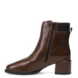 Botas cortas de cuero color marrón capuchino, con elástico lateral negro, hebilla decorativa y taco cuadrado.