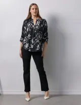Blusa de gasa estampada con flores blancas sobre fondo negro, marca Floral & Ivy. Tiene cuello a la base con escote en V y mangas tres cuartos regulables con presilla y botón.