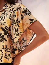 Camisa de manga corta con estampado de flores en tonos amarillo, negro y beige.
