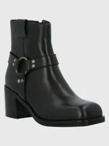Bota corta de cuero color taupe, con caña de 14 cm, taco cuadrado de 6 cm y punta cuadrada. Presenta una correa con hebilla metálica alrededor del tobillo y cierre lateral.