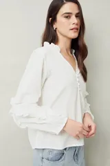 Blusa color amarillo pálido de manga larga con escote en V, mangas abullonadas con volados y botones forrados.