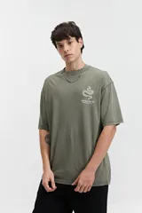 Remera oversize color verde militar con efecto acid wash y estampado en el pecho con una serpiente y texto.