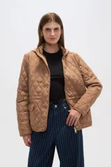 Campera capitoneada color tostado con capucha desmontable, cierre frontal con cremallera y bolsillos laterales con solapa y botón a presión.