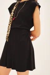 Vestido corto negro de morley con cuello redondo, elástico en la cintura y falda con capas. Incluye medallita marcaria en la espalda.