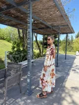 Vestido largo de corte recto con estampado abstracto en tonos marrones y blancos, cuello camisero y mangas largas.