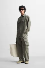 Sobrecamisa verde militar de lino, corte relaxed fit, con cuello solapa, manga larga con puños abotonados, bolsillos de parche con solapa en el pecho, aberturas laterales en el bajo y cierre frontal abotonado.