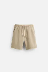 Bermuda color beige de denim de algodón, corte relaxed fit, con cintura elástica ajustable con cordón, bolsillos frontales y traseros.