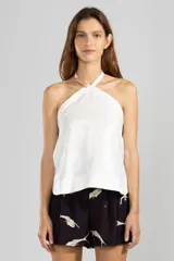 Top halter blanco de lino italiano con hilo metalizado y escote halter que se ajusta con cordón al cuello.