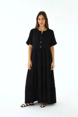Vestido largo negro de lino, con cuello mao, manga corta y botones frontales. Corte amplio con volados en la falda.