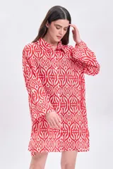 Vestido camisero corto de algodón con estampado geométrico en tonos rojo y blanco, cuello camisero, mangas largas y corte recto.