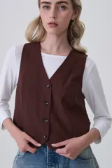 Chaleco negro de poliéster con escote en V y cierre frontal de botones. Diseño holgado.