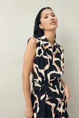 Vestido midi sin mangas confeccionado en viscosa fluida, con cuello camisero, estampado abstracto en negro y beige, y lazo para ajustar en la cintura.