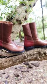 Botas de media caña color marrón de cuero vacuno, con detalle de costuras en la capellada y contrafuerte color bordó. Suela de caucho con taco bajo.
