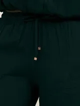 Pantalón palazzo negro de crepe con cintura elastizada, bolsillos laterales y terminaciones con logo en cobre.