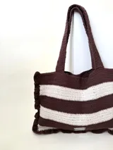 Bolso tipo tote tejido a crochet, con hilo 100% algodón, a rayas horizontales color crema y lila, con volados en los bordes y manijas reforzadas.