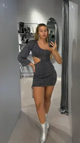 Minivestido negro con brillos plateados, de un solo hombro, manga larga y abertura en la cintura.