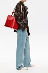 Bolso tote negro de cuero vacuno con doble asa corta y correa de tela extraíble. Interior con tres compartimentos y bolsillo con cremallera. Logo metálico de la marca en el frente.
