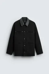 Parka negra de algodón con cuello solapa de cuero sintético, corte recto, acolchada, con bolsillos de parche y cierre frontal con botones.