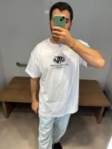 Remera blanca de algodón premium, corte oversize, con estampado en serigrafía en la espalda con logo y listado de ciudades.