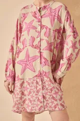 Vestido camisero corto de lino color blanco con estampado de estrellas de mar y algas en azul. Tiene cuello mao, mangas largas y cierre frontal con botones.