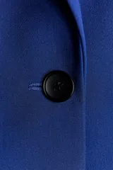 Blazer azul eléctrico de corte entallado, con cuello de solapa, manga larga con hombreras, bolsillos frontales con solapa y cierre frontal con un botón.
