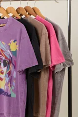 Remera negra con efecto acid wash, corte holgado y estampa frontal de una mujer con gafas de sol.