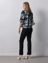 Blusa de gasa estampada con flores verdes sobre fondo blanco, de la marca Sioni. Tiene mangas cortas amplias con abertura y botón.
