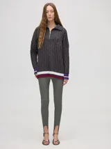 Sweater tejido de algodón color rosa claro, con cuello polo con cierre de cremallera metálica y mangas largas con puños a rayas de colores.