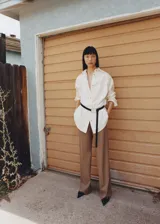 Pantalón de vestir color beige, de corte wide leg, con trabillas, tejido fluido, detalle de pinzas, dos bolsillos laterales y cierre oculto de botón, gancho y cremallera.