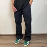 Jean de hombre, color negro deslavado, corte baggy o ancho, con tiro medio y pierna recta que cae holgada sobre el calzado.