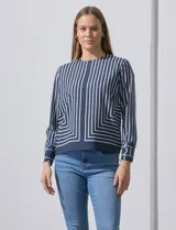 Blusa de gasa estampada a rayas verticales blancas y negras, marca Sioni. Espalda con abertura y botón. Manga larga con puño y botón.