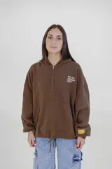 Canguro marrón con capucha, cierre de cremallera corto, bolsillo tipo canguro y cordón ajustable en el ruedo. Estampado con el texto "Pulau Design Dept." en el pecho.