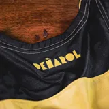 Musculosa de básquet Puma del Club Atlético Peñarol, modelo Home 2025. Diseño a rayas verticales amarillas y negras con logo de Puma y escudo del club.