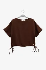 Top marrón de manga corta con cuello redondo y lazos ajustables en los laterales.