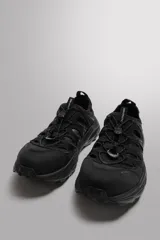 Zapatilla deportiva color beige con aberturas laterales, ajuste de cordones y suela de goma.