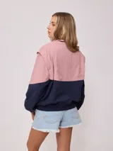 Campera negra tipo rompevientos de nylon con cierre frontal y bolsillos laterales.