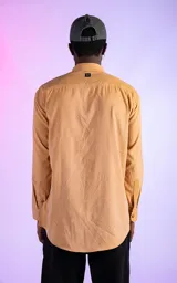Camisa manga larga color mostaza de calce relaxed fit. Cuenta con detalles de canesú en frente y espalda, y aberturas en laterales. Su tela gamuzada le brinda a la prenda una textura de exclusiva suavidad.
