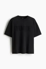 Remera negra de corte holgado confeccionada en tejido de algodón pesado con cuello redondo ribeteado y diseño estampado con la palabra "Venice" en el frente.