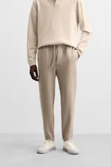 Pantalón negro de corte cropped, con cintura elástica ajustable con cordón, bolsillos laterales y traseros de vivo. El bajo tiene terminación con vuelta.