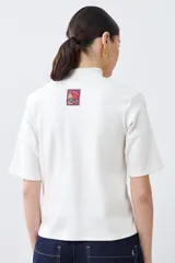 Remera de media polera color crudo, de manga corta y corte recto.