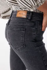 Pantalón de jean elastizado negro con corte acampanado y volados en el ruedo.
