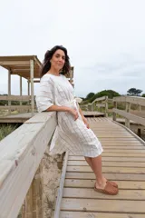 Túnica blanca con rayas verticales finas color dorado, corte holgado, mangas cortas amplias y lazo en la cintura.