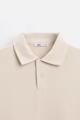 Polo manga larga gris con cuello solapa y cierre frontal de botonadura.