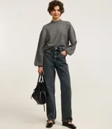 Suéter gris de punto, corte corto, con cuello alto y mangas largas abullonadas.