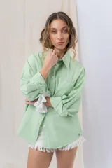 Camisa color crema de algodón liviano, calce oversize, con cuello camisero, cierre abotonado, mangas largas con opción de arremangado y dos bolsillos frontales con solapa.